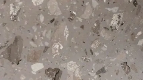 Breccia Bruna engineered marble: taupe ground with large dark brown-grey fragments among cream and speckled pieces