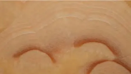Red Dragon Onyx slab: sweeping rust-red arcs on a soft peach ground