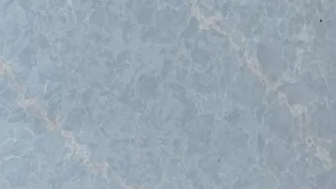 Blu Polvere quartz slab: clouded powder blue with blush-beige diagonal veins