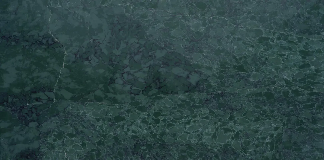 Verde Alpi quartz slab: deep forest green with darker clouding and fine pale veins