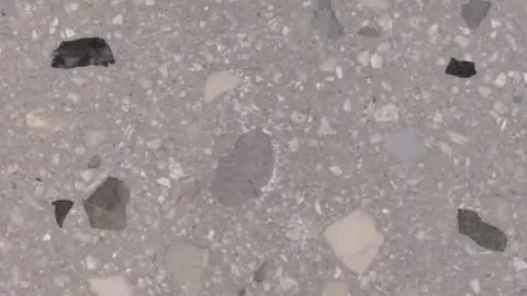 Tufo terrazzo: warm taupe-grey ground with sparse large beige and grey chips, plus a few black ones